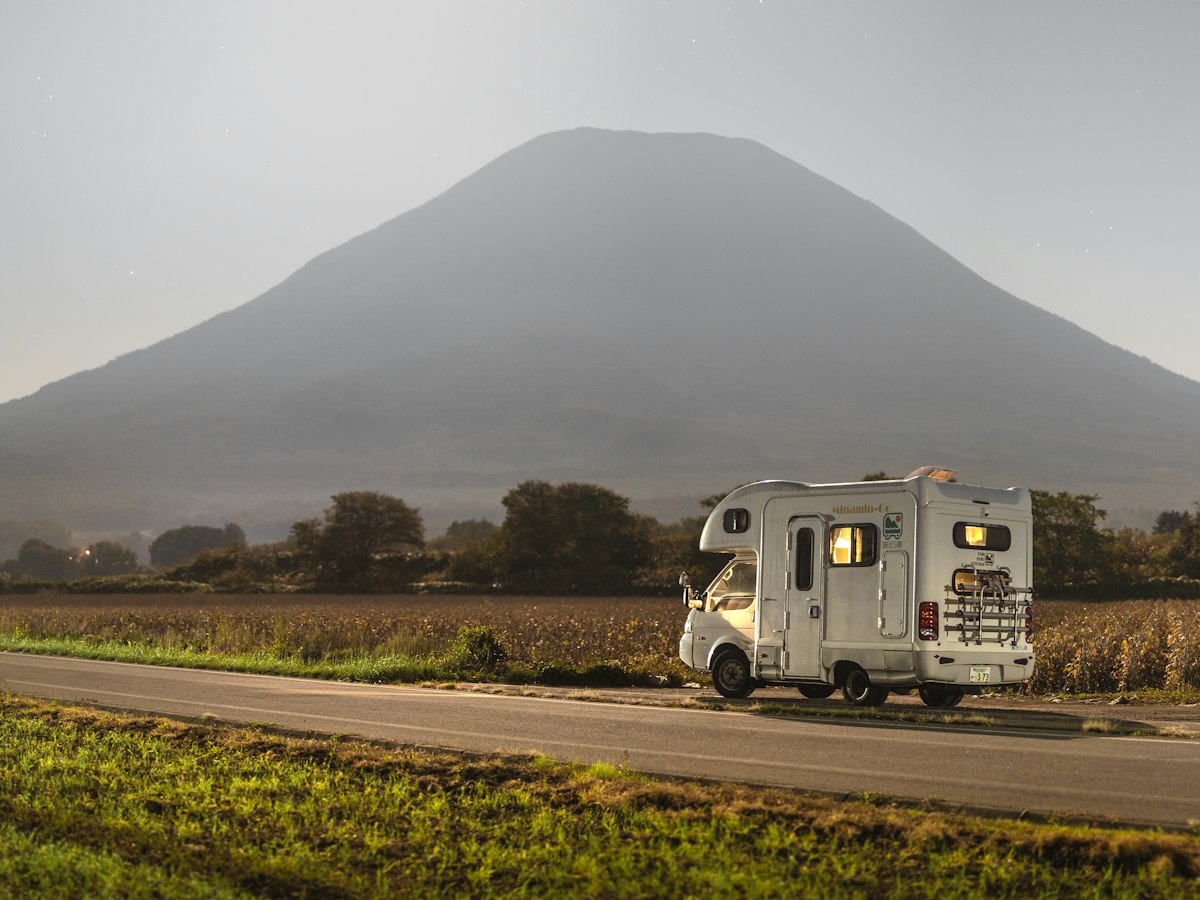 A camper van parked on a mountain road at dusk